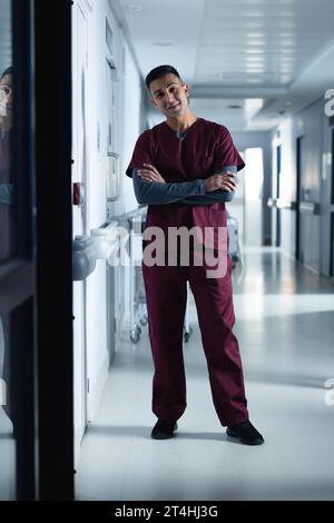 Ritratto di felice medico maschio birazziale che indossa scrub in ospedale Foto Stock