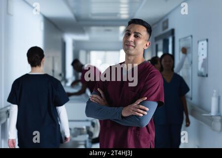 Ritratto di felice medico maschio birazziale che indossa scrub in ospedale Foto Stock