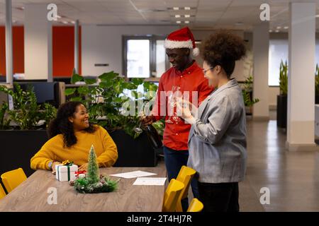 Tre persone d'affari informali felici e diversificate che tengono occhiali in ufficio, spazio fotocopie Foto Stock