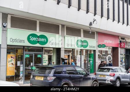 Shrewsbury, Shropshire, Inghilterra, 1 maggio 2023. Persone che passano davanti agli ottici Specsavers e agli audiologi Amplifon in strada con auto parcheggiate. Foto Stock