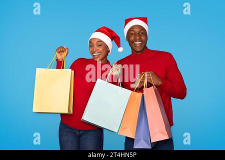 Borse per lo shopping Happy Black sposi che pubblicano durante le festività, sfondo blu Foto Stock