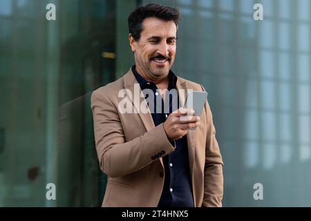 Felice uomo d'affari maturo che usa il cellulare all'aperto Foto Stock
