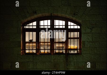 Le luccicanti menorah di Hanukkah bruciano brillantemente con otto candele in una finestra ad arco nell'ultima notte della celebrazione del Festival delle luci a Jeru Foto Stock