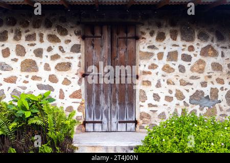 Vecchia porta in legno marrone su un muro di pietra, vista frontale, texture per foto di sfondo Foto Stock
