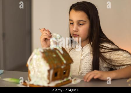 Una ragazza gioca con una casa di pan di zenzero per la decorazione tradizionale di Natale Foto Stock