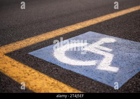 Cartello parcheggio per disabili su asfalto con linee gialle Foto Stock