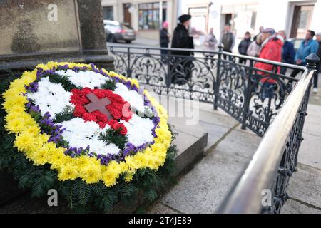 Lutherstadt Eisleben, Germania. 31 ottobre 2023. Dirk Wellmitz (l), guida della città nel ruolo di Martin Lutero, parla ai turisti sulla piazza del mercato. In primo piano c'è la rosa di Lutero fatta di fiori. Il giorno della riforma, i visitatori sono stati guidati attraverso il luogo di nascita del riformatore. Credito: Sebastian Willnow/dpa/Alamy Live News Foto Stock