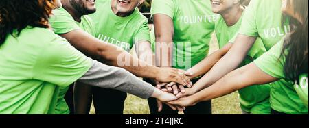 Gruppo di volontari che si impilano le mani per festeggiare insieme - progetto ambientale di beneficenza e concetto di lavoro di squadra Foto Stock