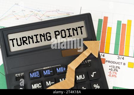 Concetto aziendale. Sui grafici aziendali è presente una calcolatrice sullo schermo con l'iscrizione "PUNTO DI SVOLTA" Foto Stock