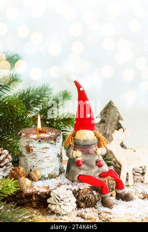 Decorazione natalizia con babbo natale giocattolo, candela in fiamme, rami di abete e coni di pino Foto Stock