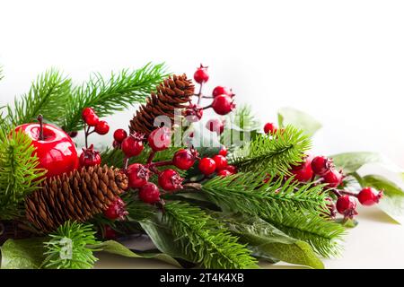 Decorazione natalizia con abete, coni di pino, mele rosse e bacche di holly Foto Stock