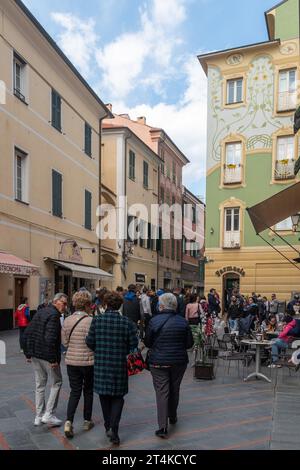 Vista sulla strada di via Antonio Ghilini affollata di gente nel centro storico della destinazione turistica pupolare in primavera, Loano, Savona, Liguria Foto Stock