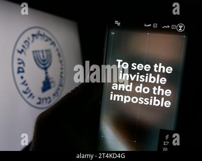 Persona che tiene il cellulare con il sito web dell'agenzia di intelligence nazionale israeliana Mossad davanti al logo. Concentrarsi sul centro del display del telefono. Foto Stock