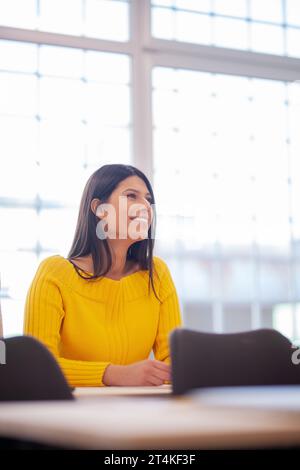 Studente che ascolta un docente in classe. Una giovane donna intelligente studia in un college. Foto Stock