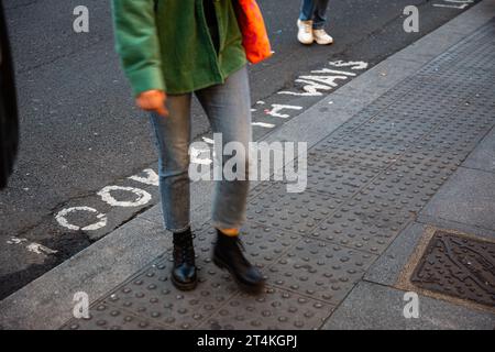 Le lettere "Look Both Ways" sono dipinte su New Oxford Street. Attraversamento pedonale nel borgo londinese di Camden, Regno Unito. Foto Stock