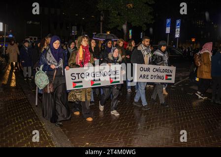 L'Aia, Olanda meridionale, Paesi Bassi. 23 ottobre 2023. Le madri e i manifestanti tengono cartelli che esprimono la loro opinione mentre camminano attraverso il centro della città dell'Aia in una marcia silenziosa per i 2.055 bambini uccisi dai bombardamenti israeliani lungo la striscia di Gaza. Circa 150 madri hanno partecipato a una marcia silenziosa questa sera, per lo più vestite di nero, alcune con candele accese; per ricordare i bambini uccisi a Gaza dai bombardamenti israeliani. La marcia partì per il Korte Voorhout e alla fine finì al Turfmarkt. I dati del Ministero della salute palestinese controllato da Hamas a Gaza hanno detto che il bilancio delle vittime è r Foto Stock