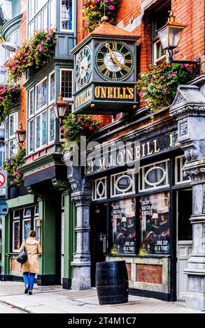 Facciata colorata del tradizionale o'Neills Pub di Dublino, con orologio d'epoca e cestini appesi, nel centro di Dublino, in Irlanda Foto Stock