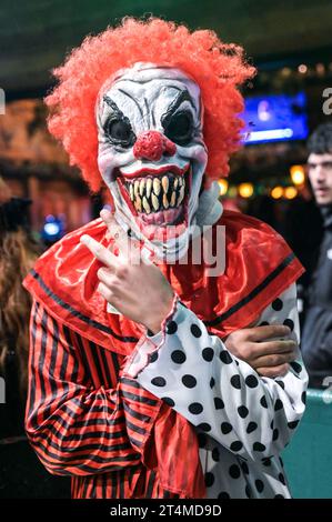 Broad Street, Birmingham, 31 ottobre 2023 - migliaia di festeggiamenti sono usciti martedì sera per festeggiare Halloween. La pioggia ha iniziato a diventare leggera, diventando pesante vicino a mezzanotte, ma ciò non ha smorzato gli spiriti. Alcuni hanno usato cappotti per ripararsi e altri hanno improvvisato con sacchetti di plastica sulla famigerata strada della vita notturna di Birmingham. Il Bier Bar di Heidi era tutto esaurito con una politica "one in, one out" imposta perché le code si estendevano lungo la strada in una delle loro notti più trafficate dell'anno. Nonostante il freddo e il clima umido, ciò non ha impedito alcuni costumi sorprendenti, tra cui un ragazzo con una felpa con cappuccio Just Stop Oil arancione, Una donna dr Foto Stock