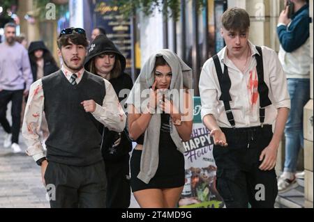 Broad Street, Birmingham, 31 ottobre 2023 - migliaia di festeggiamenti sono usciti martedì sera per festeggiare Halloween. La pioggia ha iniziato a diventare leggera, diventando pesante vicino a mezzanotte, ma ciò non ha smorzato gli spiriti. Alcuni hanno usato cappotti per ripararsi e altri hanno improvvisato con sacchetti di plastica sulla famigerata strada della vita notturna di Birmingham. Il Bier Bar di Heidi era tutto esaurito con una politica "one in, one out" imposta perché le code si estendevano lungo la strada in una delle loro notti più trafficate dell'anno. Nonostante il freddo e il clima umido, ciò non ha impedito alcuni costumi sorprendenti, tra cui un ragazzo con una felpa con cappuccio Just Stop Oil arancione, Una donna dr Foto Stock