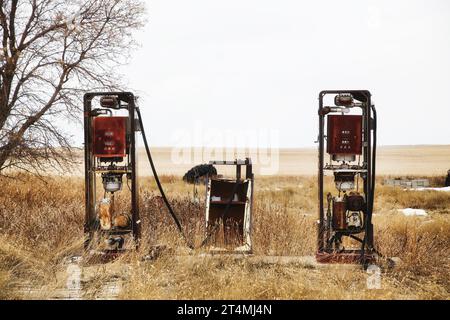 Due pompe carburante vecchie e danneggiate in un panorama primaverile Foto Stock