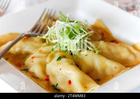 Piatto di gnocchi pieroghi in salsa in un ristorante o caffetteria, su un piatto Foto Stock