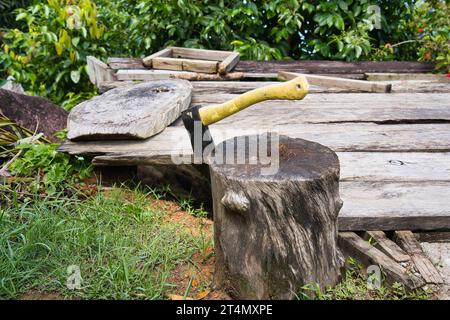 Ascia con manico giallo su legno per il taglio del legno Foto Stock