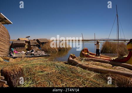 Un uomo di Uros in piedi su una barca di canne vicino alla sua isola galleggiante sul lago Titicaca Foto Stock