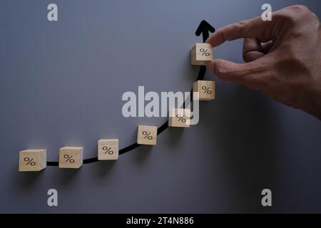 Disporre a mano un cubo di legno con l'icona della percentuale. Concetto di aumento del tasso di interesse. Foto Stock