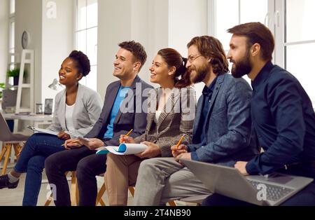 Colleghi soddisfatti gli imprenditori ascoltano e registrano informazioni durante la formazione aziendale. Foto Stock
