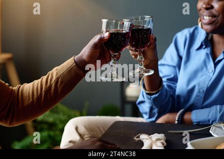 Concentratevi sulle mani di giovani coppie eterosessuali afroamericane che brindano con occhiali da vista sedendosi davanti alla macchina fotografica a un tavolo nel ristorante Foto Stock