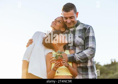 La famiglia amorevole sorride e abbraccia, godendosi del tempo di qualità insieme in campagna. Foto Stock