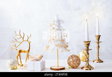 Christmas winter still life with burning candles, gift box and Christmas decorations on pastel light background. Christmas composition for home Foto Stock