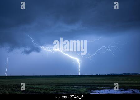 Fulmini eccezionalmente luminosi colpiscono la terra durante un forte temporale notturno Foto Stock