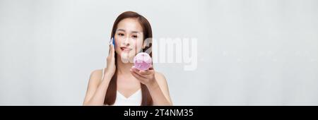 Striscione di donna che usa la polvere per ritoccare il suo viso Foto Stock