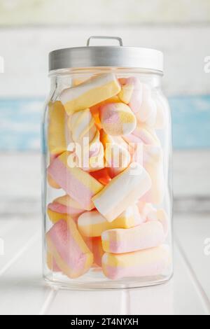 Dolci marshmallow colorati in barattolo sul tavolo bianco della cucina. Foto Stock