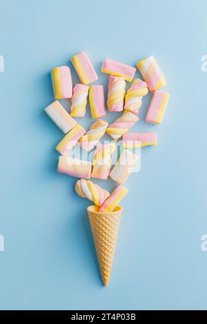 Dolci marshmallow colorati in cono gelato su sfondo blu. Vista dall'alto. Foto Stock