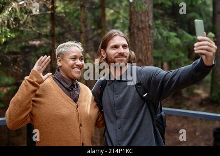 Giovani coppie che hanno videochiamato su smartphone durante le loro escursioni nella foresta Foto Stock