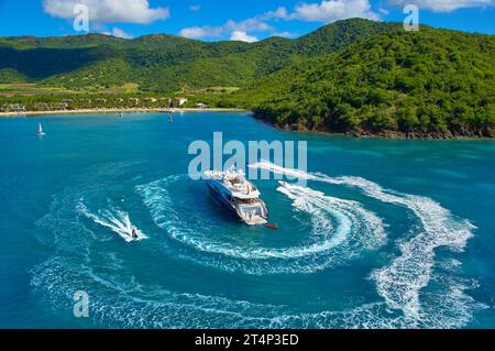 Superyacht all'ancora in una baia isolata ad Antigua con gli ospiti che si divertono sui jet ski. Foto Stock