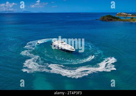 Superyacht all'ancora in una baia isolata ad Antigua con gli ospiti che si divertono sui jet ski. Foto Stock