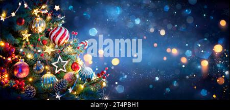 Albero di Natale con decorazioni in blu e luci bokeh - rami in vera abete con sfocatura astratta su sfondo sfocato - questa immagine contiene re 3d. Foto Stock