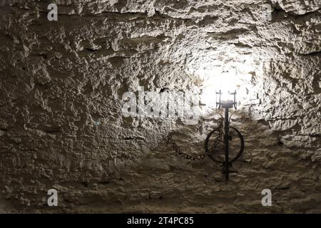 Torcia del castello medievale illuminata appesa a un muro di pietra, oggetti d'epoca e sfondo Foto Stock