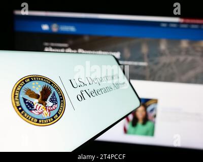 Telefono cellulare con sigillo del Dipartimento dei Veterani degli Stati Uniti (va) davanti al sito Web. Mettere a fuoco il display centrale sinistro del telefono. Foto Stock