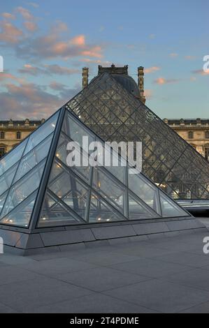 Ammira le piramidi di vetro del palazzo del Louvre al tramonto Foto Stock