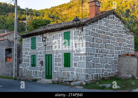 Vecchia casa residenziale in mattoni rurali con porte verdi e persiane e tetto piastrellato in un villaggio nella provincia di Avila, in Spagna. Foto Stock