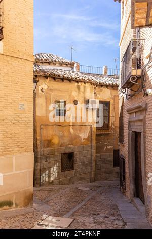 Toledo, Spagna, 09.10.21. Calle de Coliseo stretta strada medievale acciottolata con vecchie case residenziali con tetti piastrellati, facciate trascurate e pai sbiadito Foto Stock