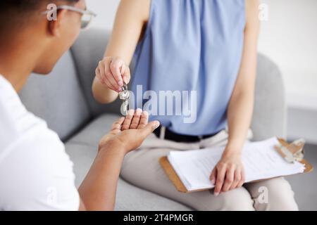 Queste sono sue. un'agenzia di noleggio irriconoscibile seduta con il suo cliente e dandogli una serie di chiavi di casa. Foto Stock