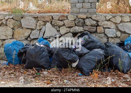 Un mucchio di sacchetti di plastica lasciati fuori sulla strada inquinando l'ambiente Foto Stock