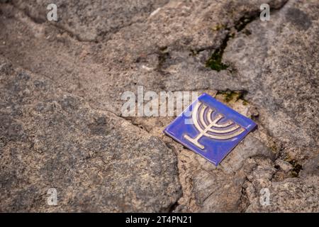 Piccola piastrella blu con il simbolo della menorah incorporata nel marciapiede dell'ex quartiere ebraico, Toledo, Spagna. Foto Stock