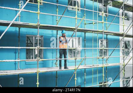 Gli ingegneri semplici amano risolvere i problemi. un giovane che parla al cellulare mentre lavora in un cantiere. Foto Stock