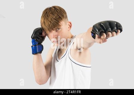 Un adolescente caucasico che indossa guanti da boxe in stile MMA Foto Stock
